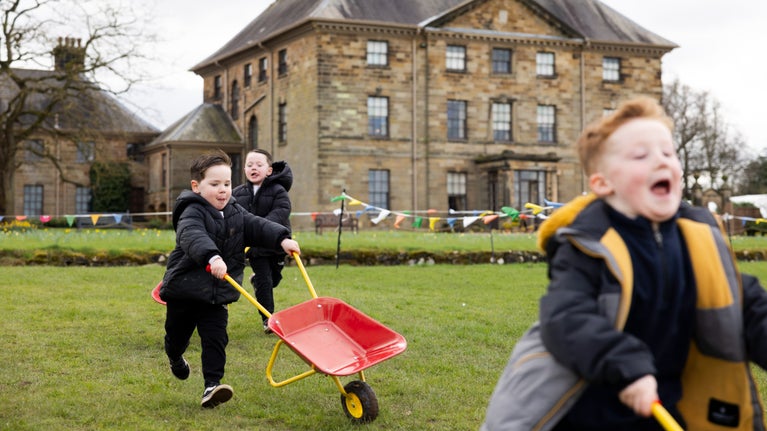 Children enjoying wheelbarrow racing during spring at Ormesby Hall
